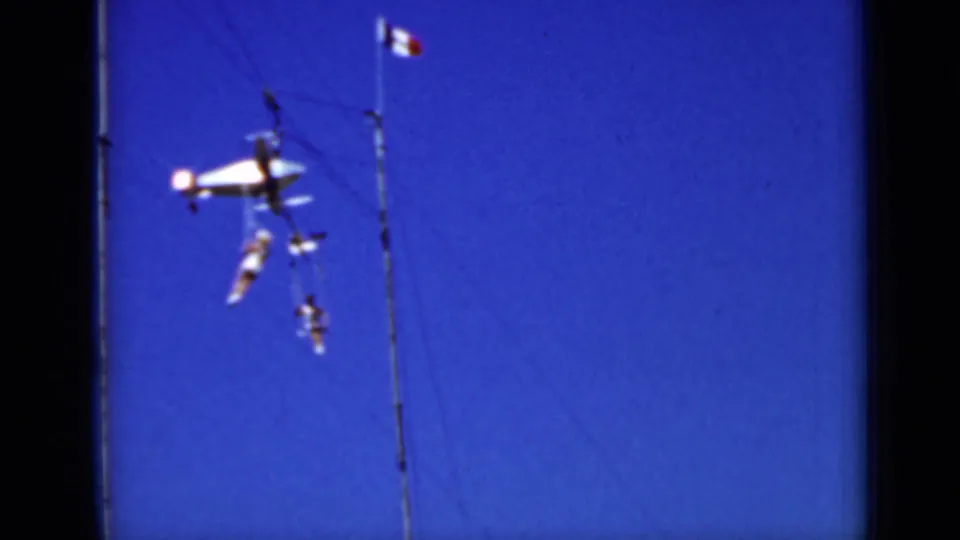 1937 San Francisco frame showing multiple circus acrobats grouped on or near high trapeze rigging beneath a flag.