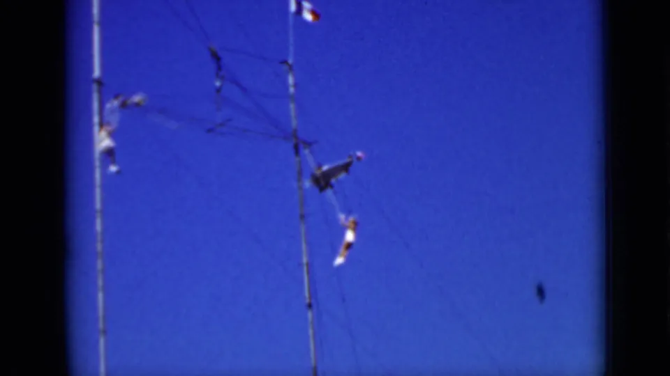 Distant aerialists move around trapeze lines and support poles in this 1937 San Francisco outdoor home-movie frame.