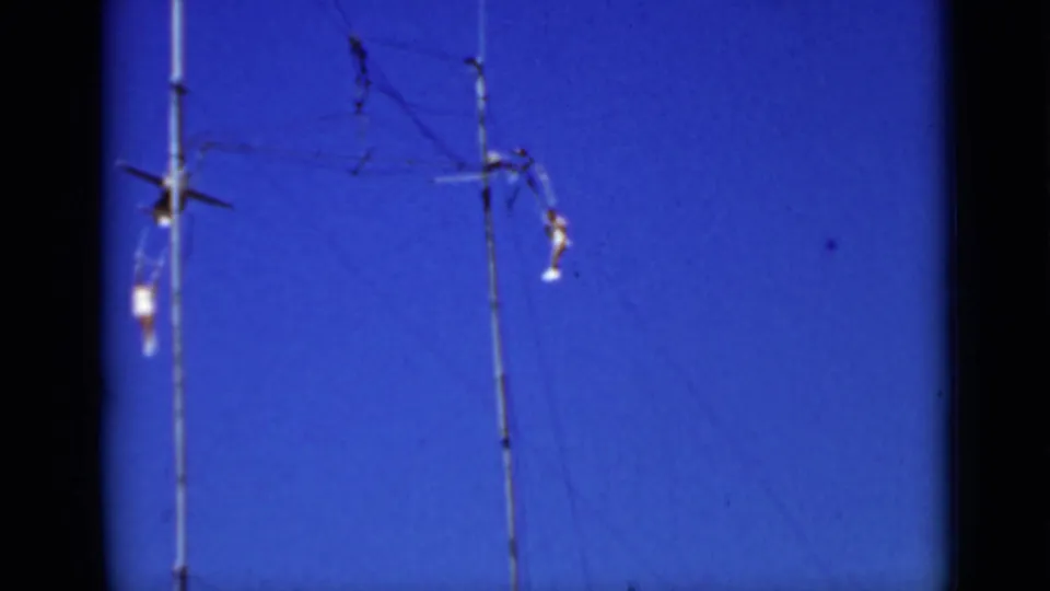 A 1937 San Francisco frame shows distant trapeze performers near high rigging and a vertical support pole.