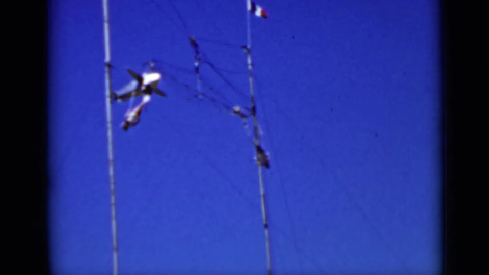 1937 San Francisco home-movie frame with an airplane-shaped mobile rotating beside thin poles and wires in the sky.