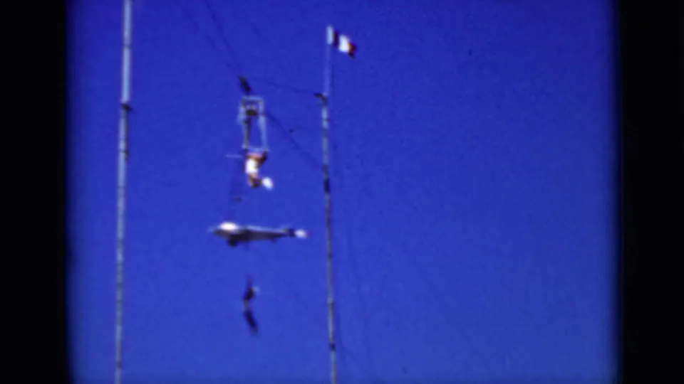 Two aerial performers appear suspended on a circus training rig, with a small tricolor flag visible above the poles in the 1937 San Francisco clip.