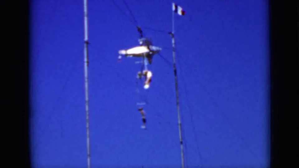 A performer hangs below the central apparatus while another is positioned higher on the rig, filmed against open sky in the 1937 home movie.
