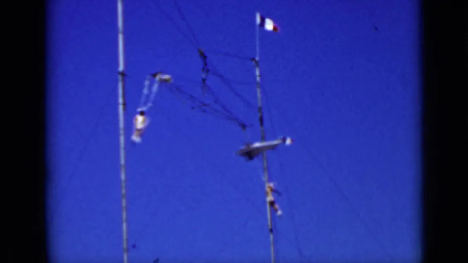 San Francisco 1937 home-movie frame of an aerial performer moving across a high rig under a small tricolor flag.
