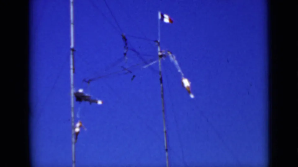 1937 San Francisco 8mm still with two aerialists separated across a high outdoor trapeze and rope rig.
