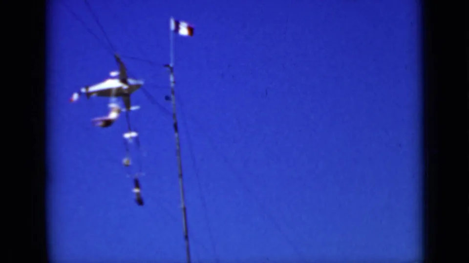 1937 San Francisco home-movie frame showing the metal airplane mobile more clearly beside a tall pole and small flag.