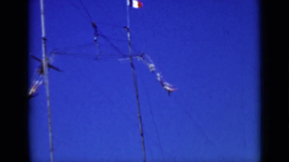 Distant trapeze artists move around suspended rigging in a 1937 San Francisco home-movie view from below.