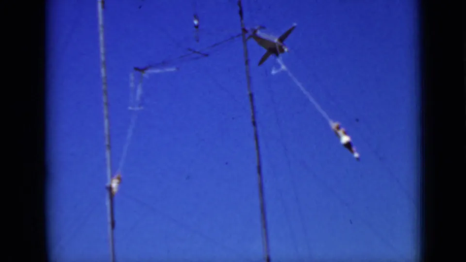 A 1937 San Francisco 8mm frame shows multiple distant aerialists rotating around trapeze rigging above the camera.
