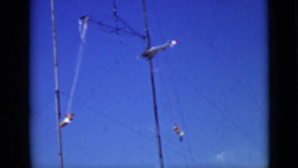Final 1937 San Francisco frame with distant trapeze performers spread across high wires and bars against blue sky.