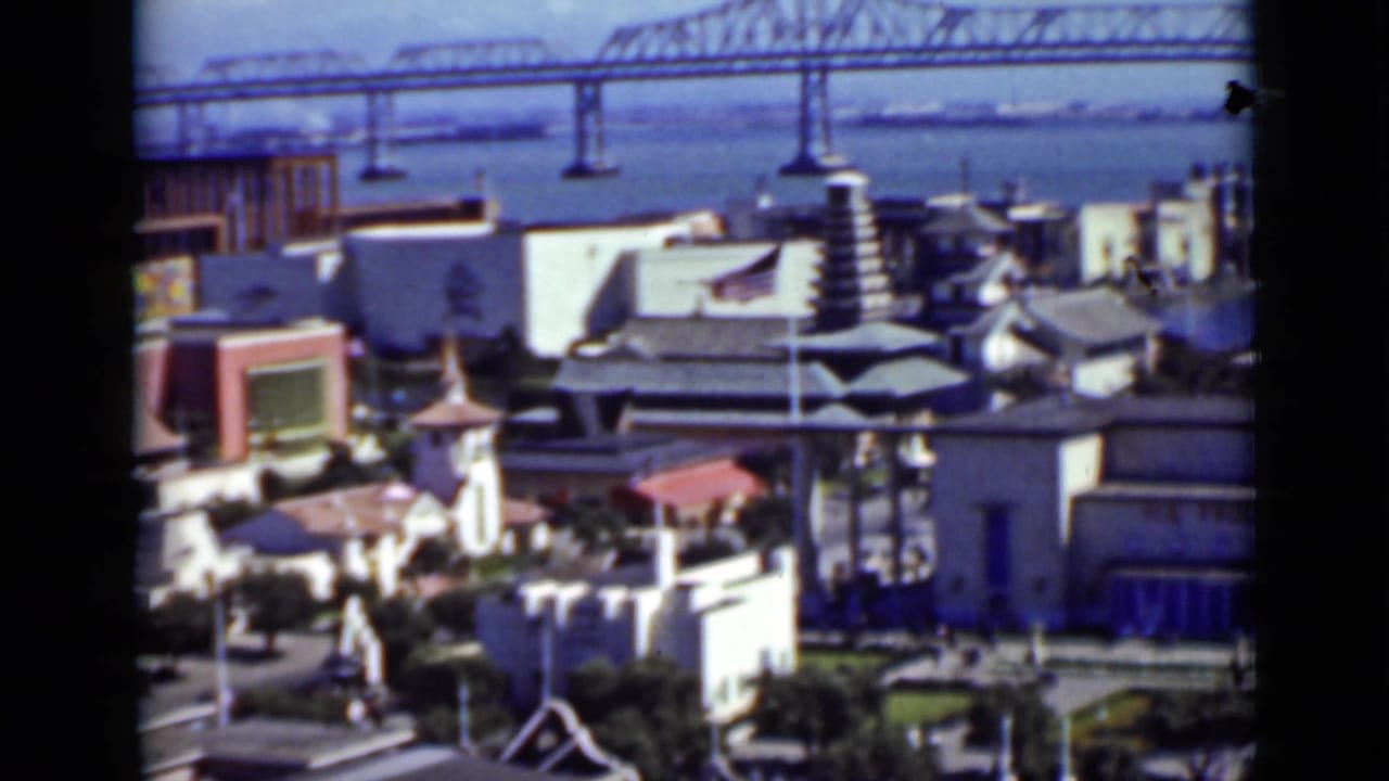 Waterfront buildings below a large suspension bridge across the bay.