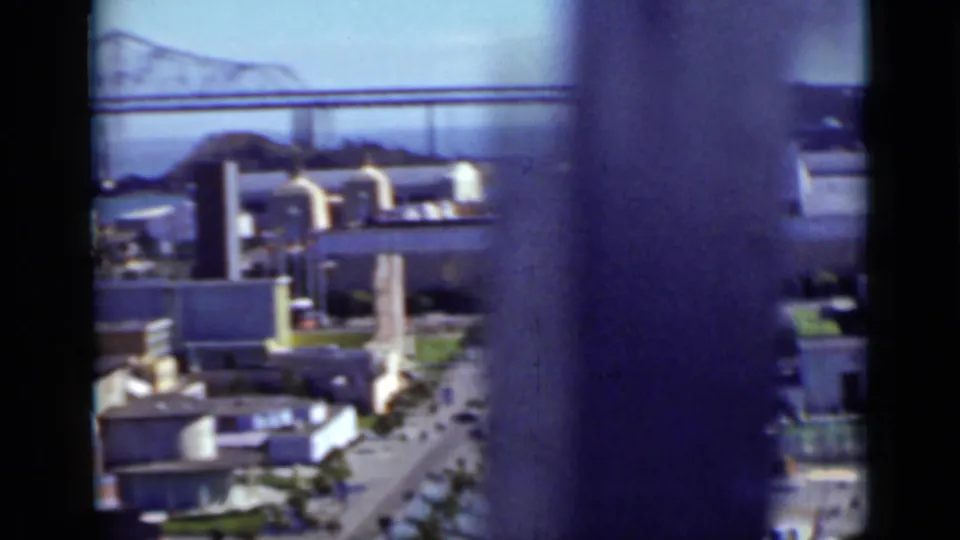 A 1937 San Francisco waterfront view with buildings, bay, and bridge partly blocked by motion blur or an intervening object.