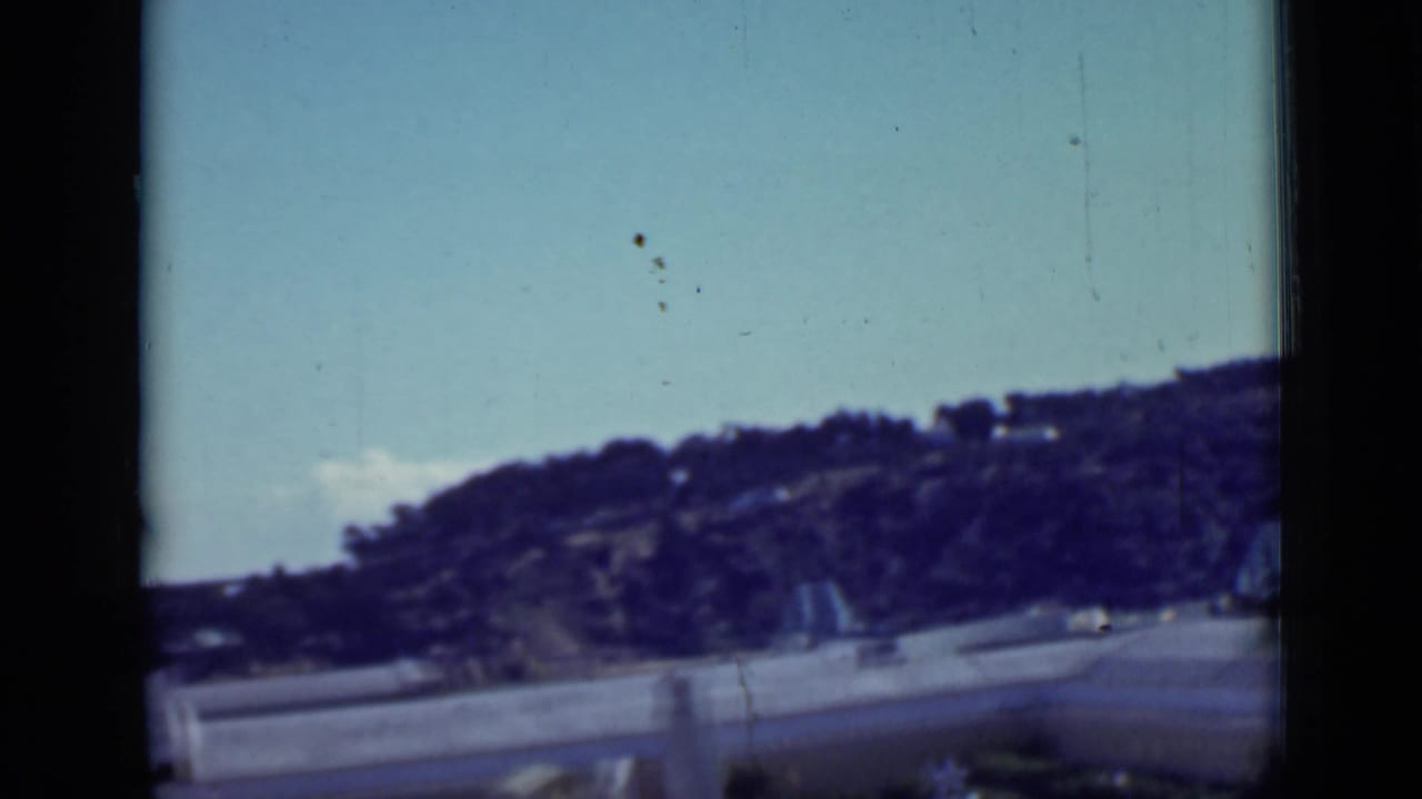 Oceanfront hillside and road seen through dark 8mm frame borders.