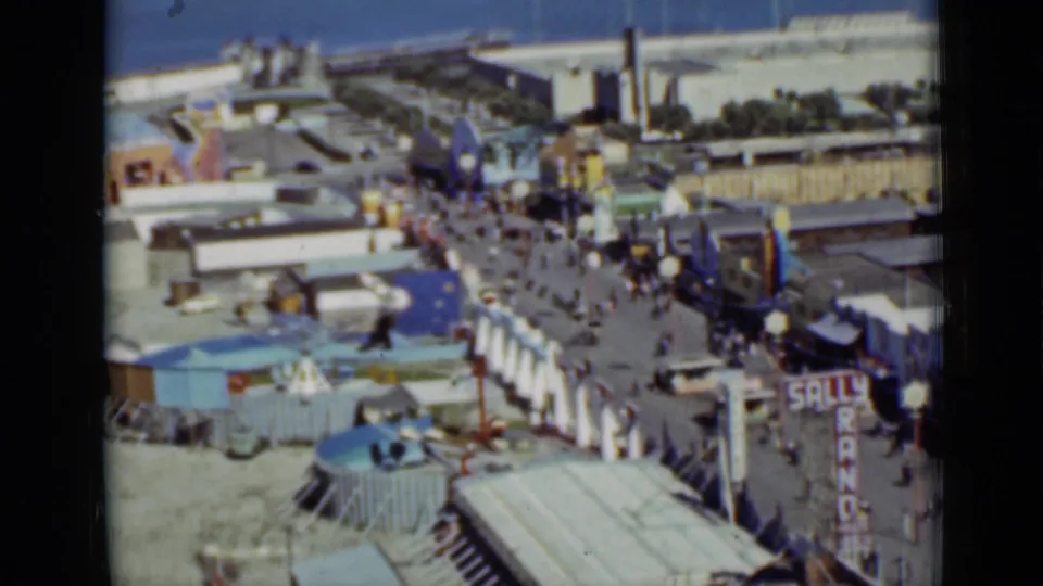 Elevated 1937 San Francisco boardwalk view with crowds, amusement structures, ocean backdrop, and a visible Sally Rand sign.