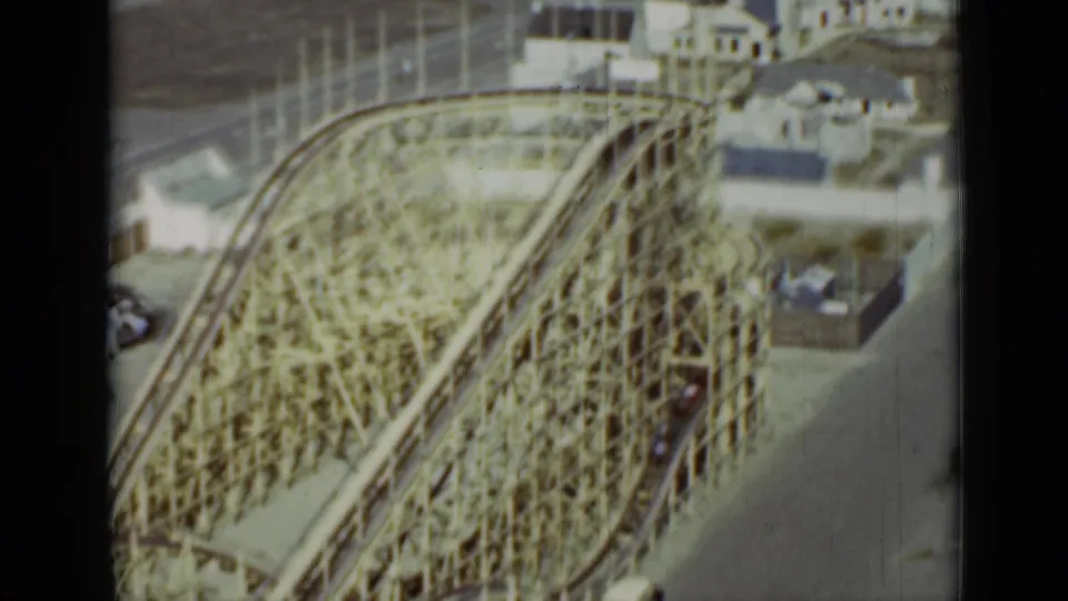 1937 San Francisco amusement-park frame showing the wooden roller coaster from above, with a coaster train moving through the structure.