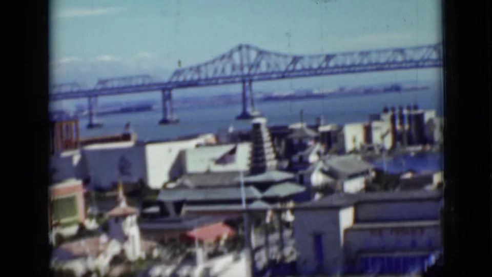 1937 San Francisco frame with a bay bridge, low buildings, and a pagoda-like amusement-area structure in the foreground.