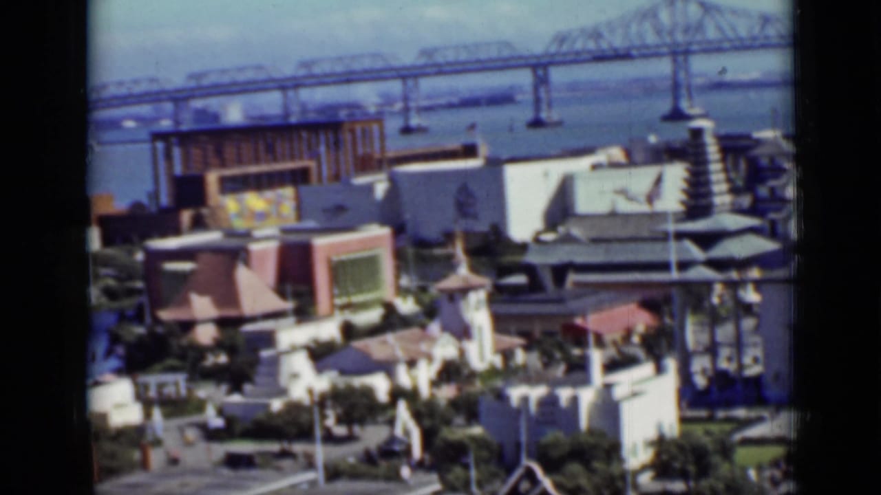 Elevated view of colorful buildings near a bay bridge.