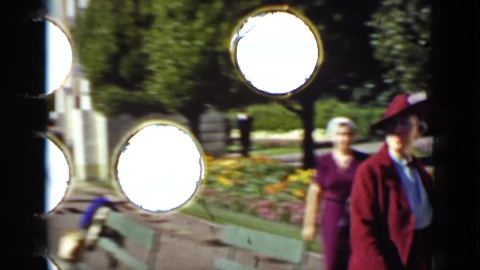 The final frame shows garden visitors moving past a green bench and flower beds, with 8mm sprocket holes visible along the scan edge.