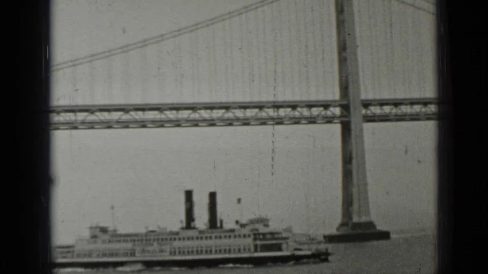 A visitor-shot 1937 San Francisco view shows the ferry low in frame beneath the Bay Bridge cables and steel deck.