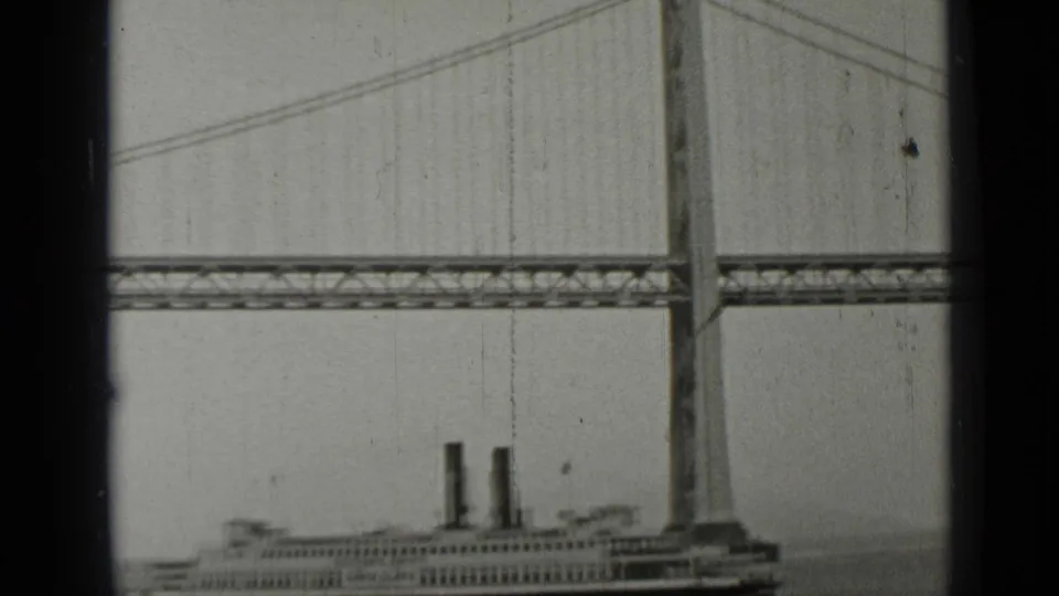 The ferry appears near the bottom of the frame as the Bay Bridge tower, deck, and suspension cables fill the 1937 San Francisco view.