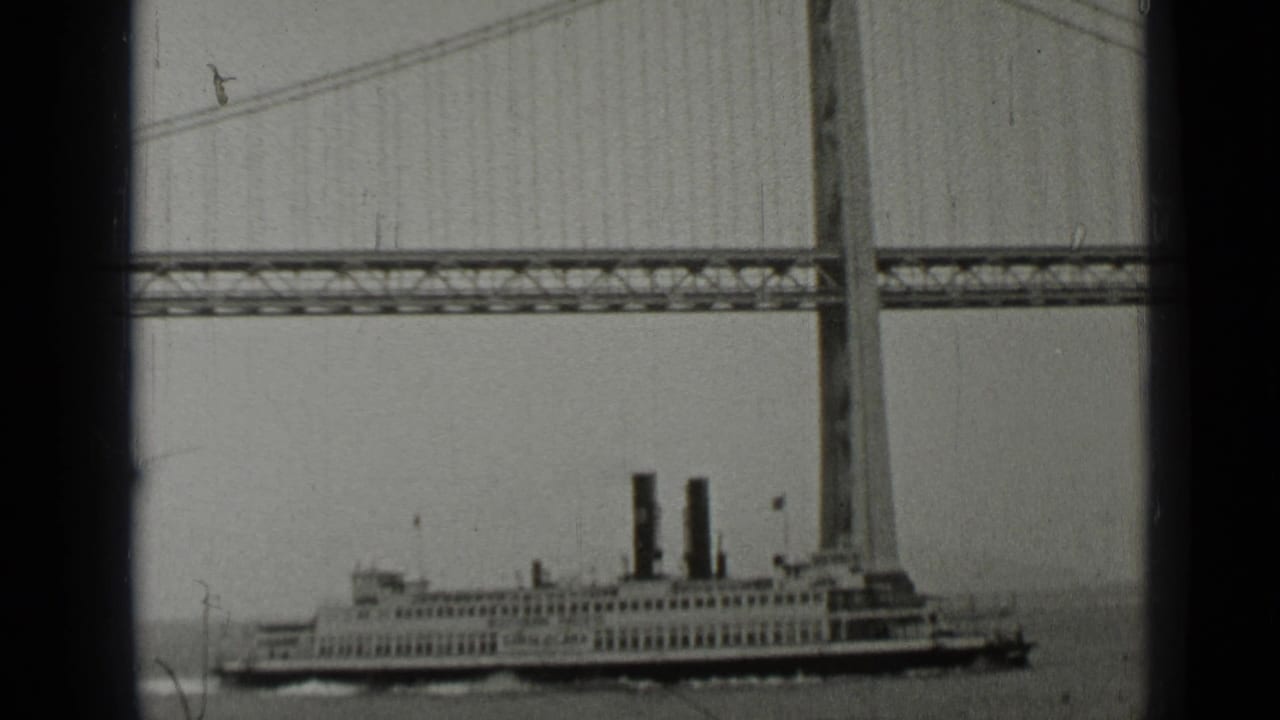 Steamship passing beneath a large suspension bridge over open water.