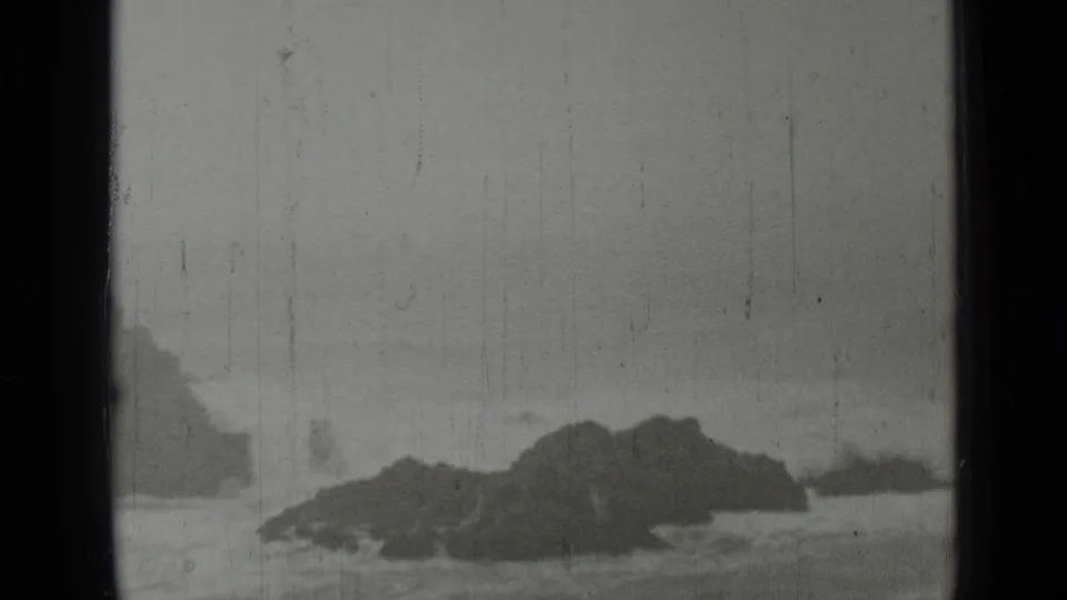 1937 San Francisco coastal home-movie frame showing white waves crashing around dark rocks beneath an overcast sky.