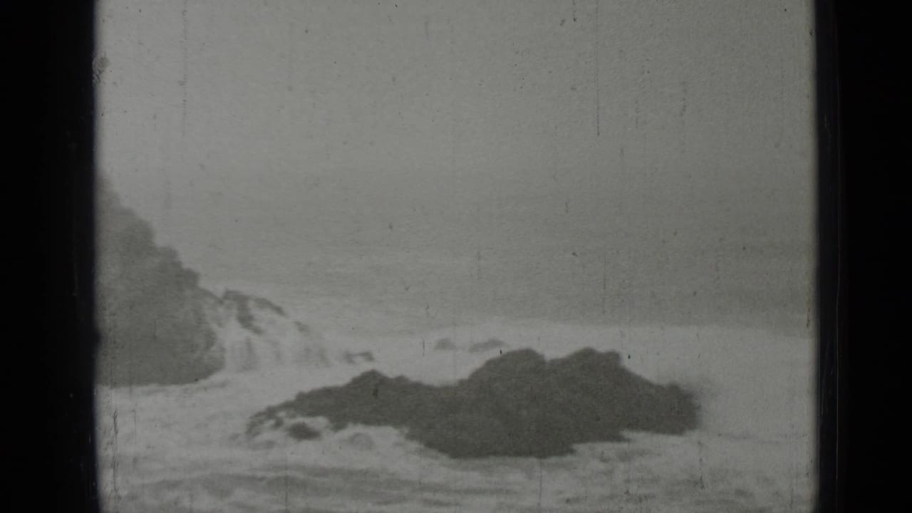 Rocky shoreline with waves breaking against dark rocks.
