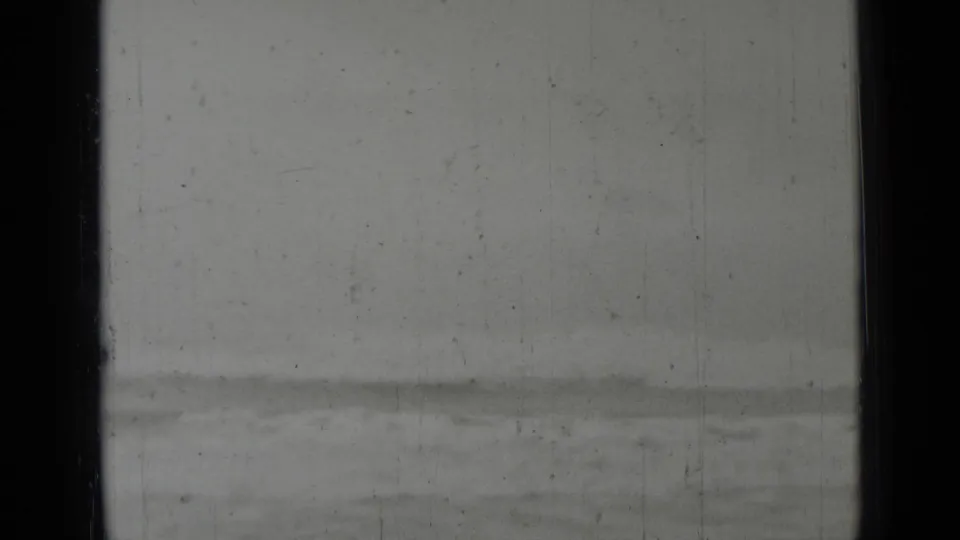 A largely blank exposed 8mm frame with a faint strip of water or shoreline along the lower edge.
