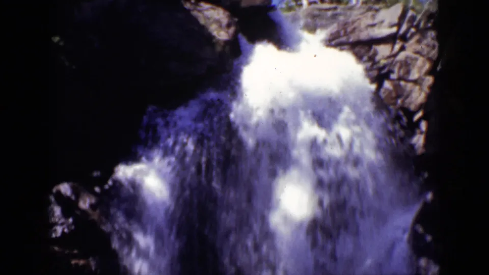 Foaming waterfall fills the lower frame as it descends through jagged Colorado rock in 1938 home-movie footage.
