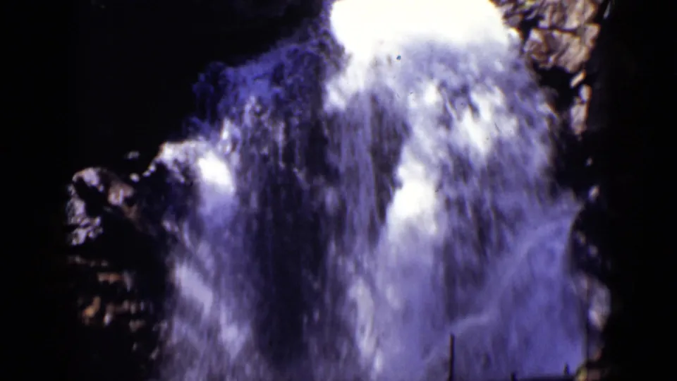 Close 1938 Colorado 8mm view of a powerful waterfall rushing between jagged, shadowed rock walls.