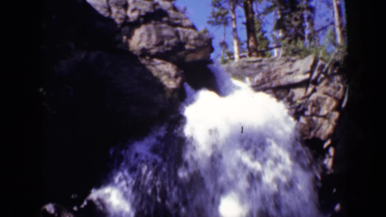 Waterfall rushes between rock walls with trees visible above.