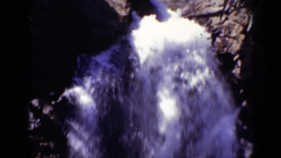 1938 Colorado 8mm frame showing a close, high-contrast view of foaming water beside rugged rock.