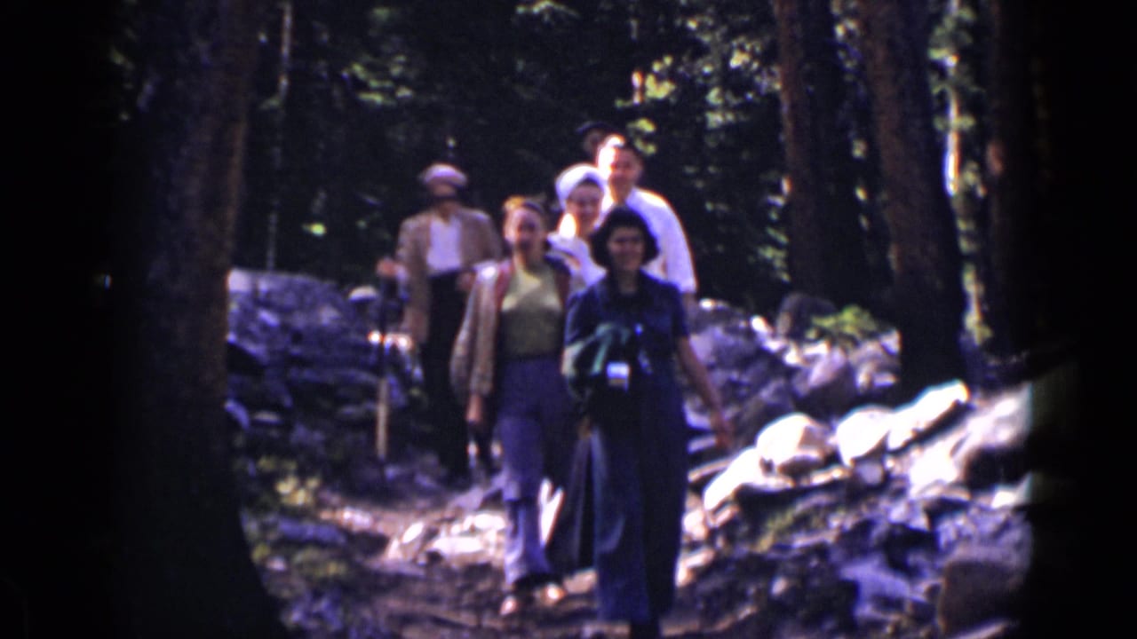Group of hikers walking toward the camera on a shaded rocky forest trail.