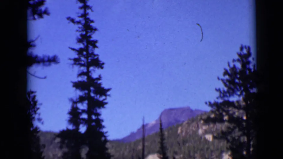Colorado mountain scenery appears beyond silhouetted pines, shifting the home movie from hikers to a scenic landscape view.