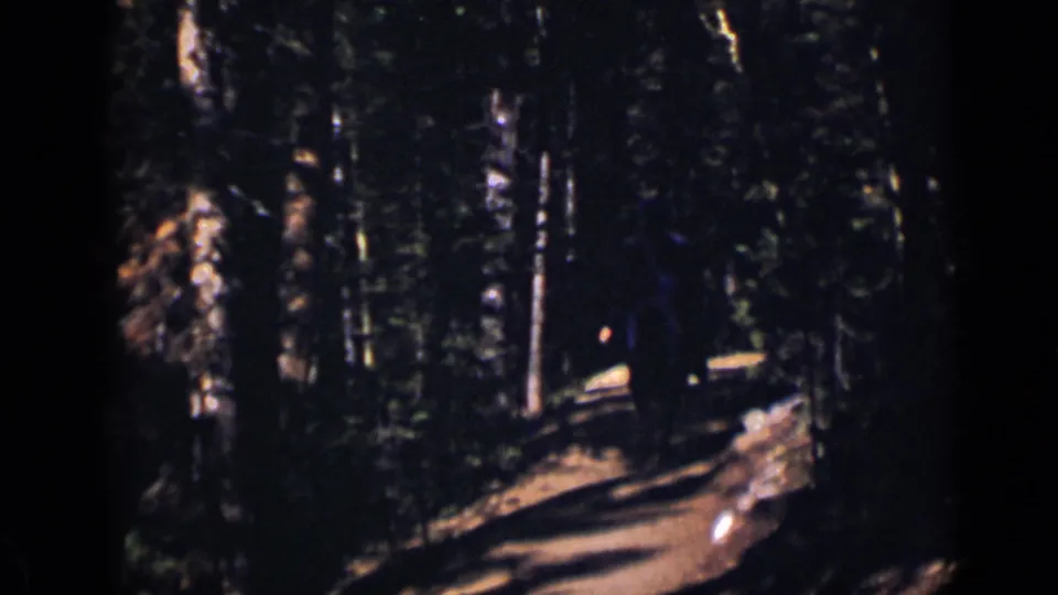 Near the end of the 1938 Colorado clip, the woman is a small dark figure moving away through the wooded path.