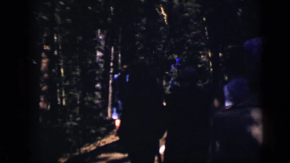 A small group walks away through the trees on a narrow wooded path in Colorado home-movie footage from 1938.