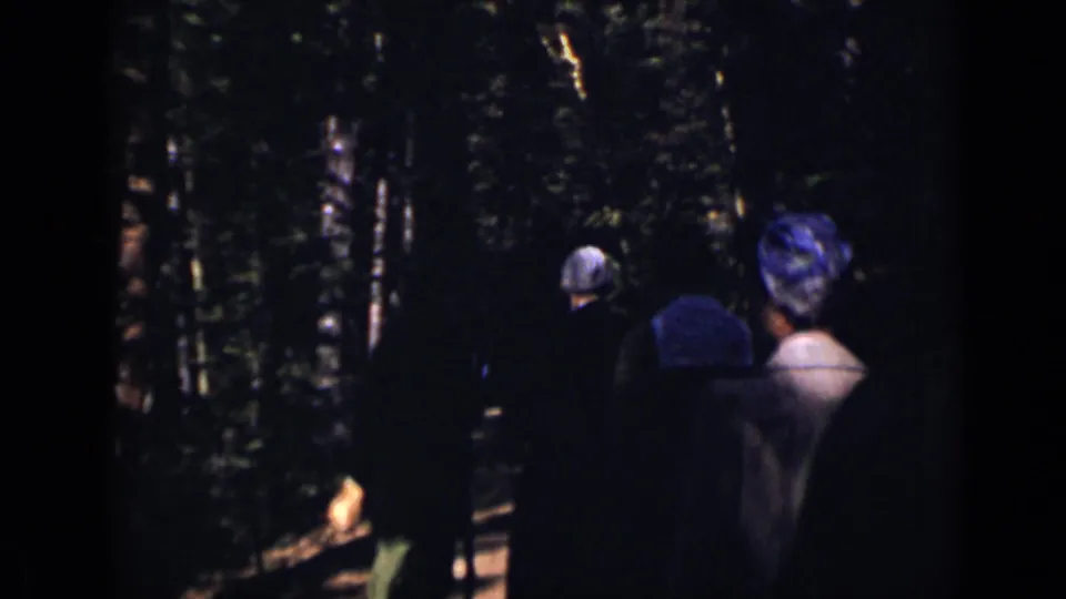 Women in coats and hats are seen from behind on a wooded Colorado path, with strong sun and shadow in 1938 8mm footage.