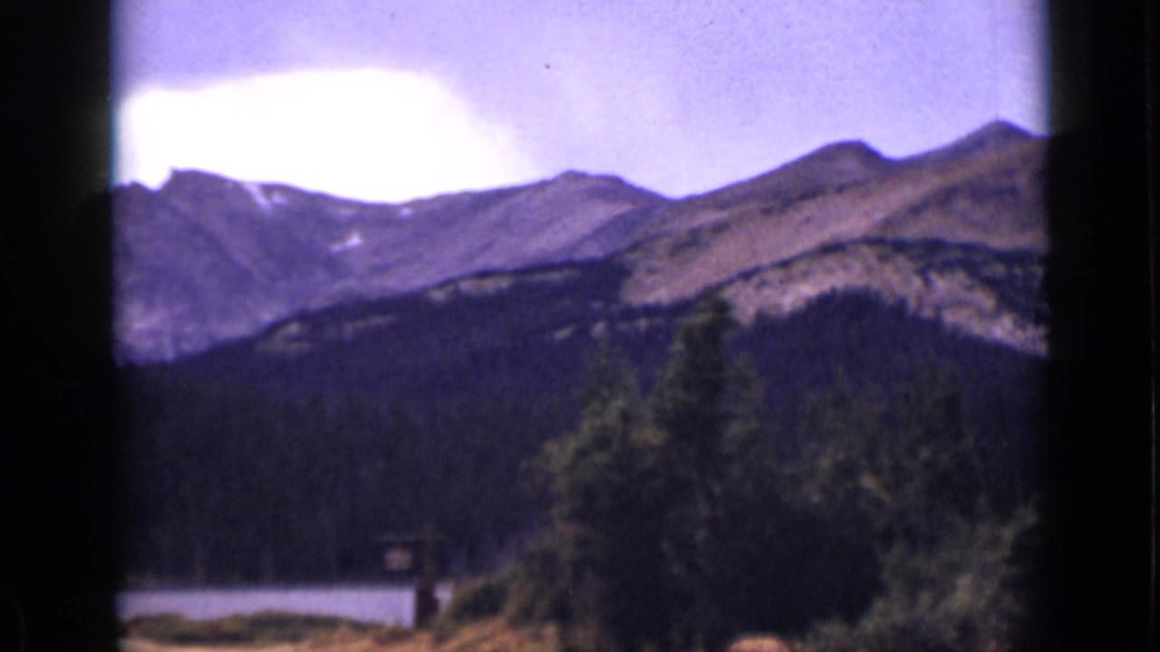 Mountain slopes and evergreen forest above a partially visible lake.