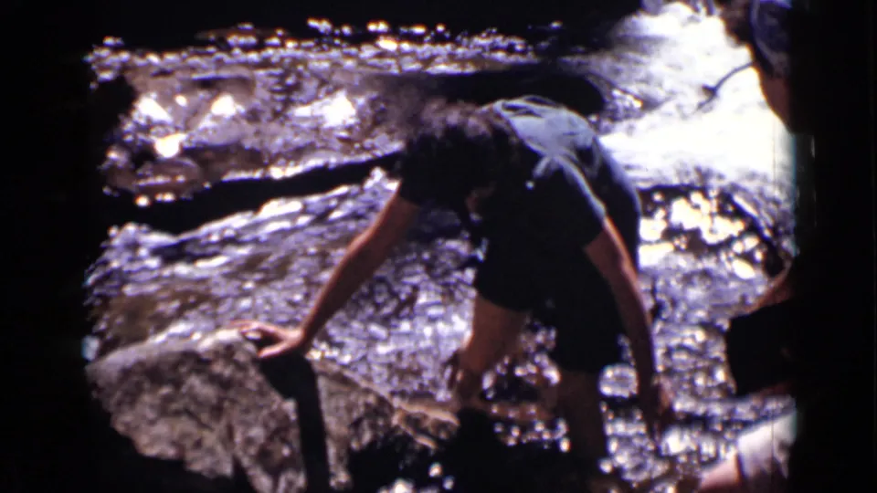 In the Colorado stream footage, the person braces a hand on a rock and steps through shallow, fast-moving water.
