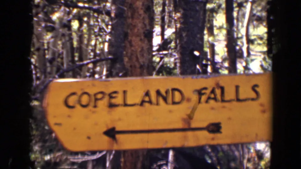 1938 Colorado frame showing a wooden Copeland Falls sign with a left-pointing arrow among trees.