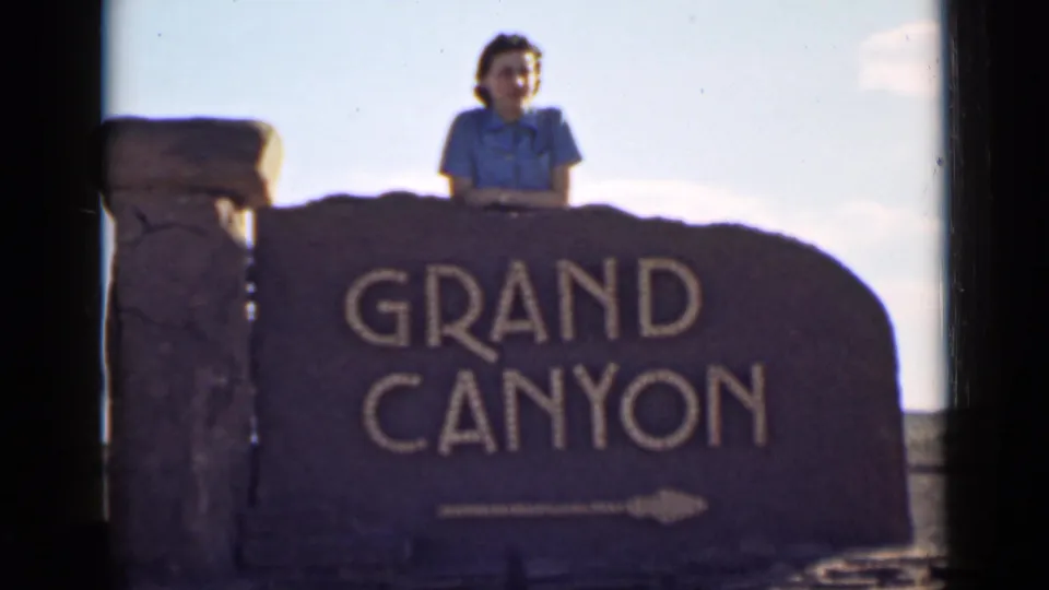 Final 1939 home-movie frame of a woman behind the Grand Canyon sign in Arizona, with soft color and visible film borders.