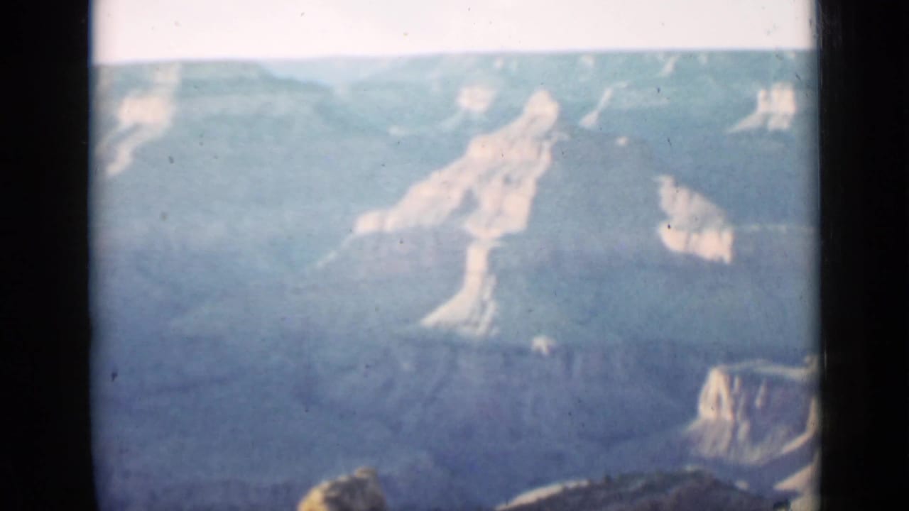 Hazy Grand Canyon rock formations seen across a dark film-frame edge.