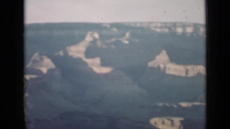1939 Arizona home-movie frame with scattered Grand Canyon formations, distant rim, and faded handheld film texture.