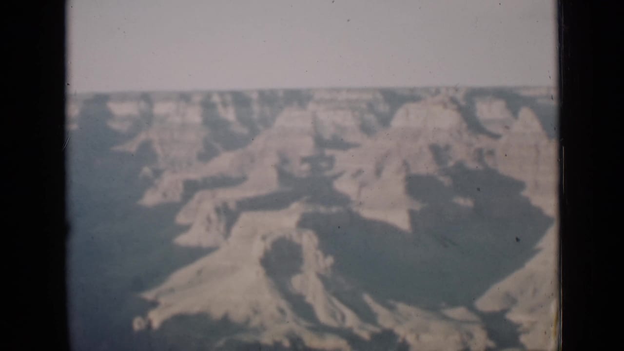 Soft color view of canyon formations within a dark 8mm frame border.