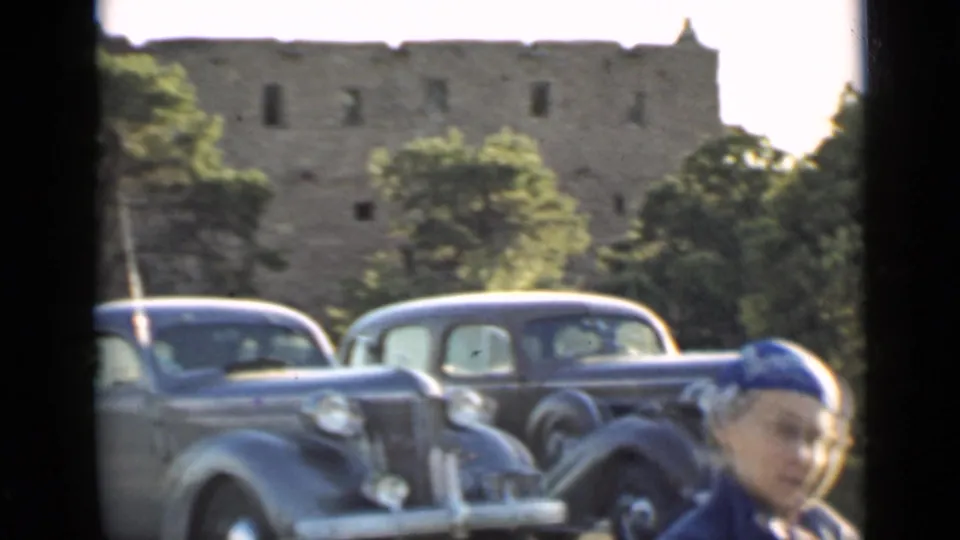 1939 Arizona frame with a 1930s car in the foreground, stone structure behind, and a woman partly visible at the edge.