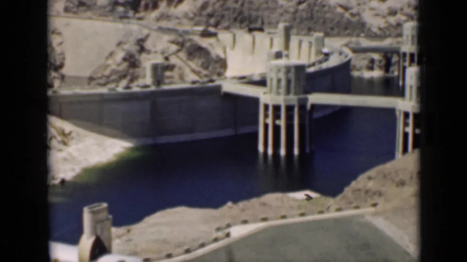 1939 Arizona home-movie view of a large concrete dam area with dark reservoir water and dry rocky terrain.