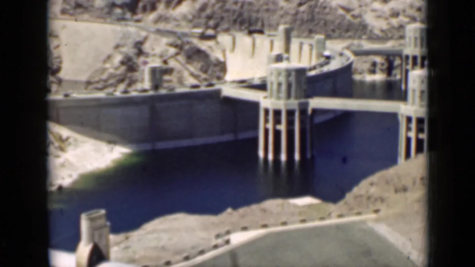 1939 Arizona dam scene showing concrete walls, reservoir water, support towers, and a dry slope in the foreground.