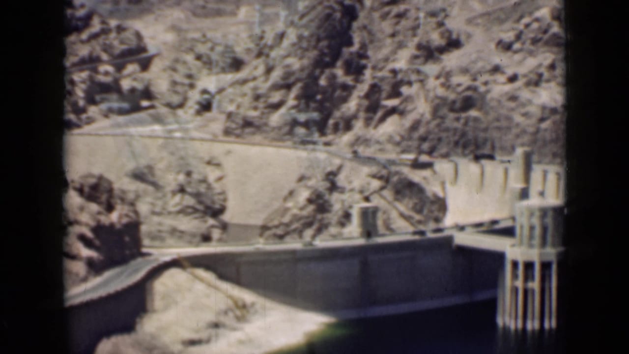 Hoover Dam viewed across a rocky canyon with dark 8mm frame borders.