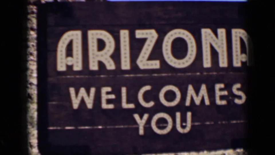 1939 8mm home-movie frame of a painted 'ARIZONA WELCOMES YOU' roadside sign confirming the travel location.