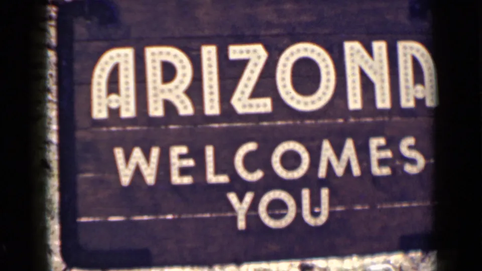 8mm frame of the Arizona Welcomes You sign, showing bold white text, dark wood, and visible contact-sheet border artifacts.