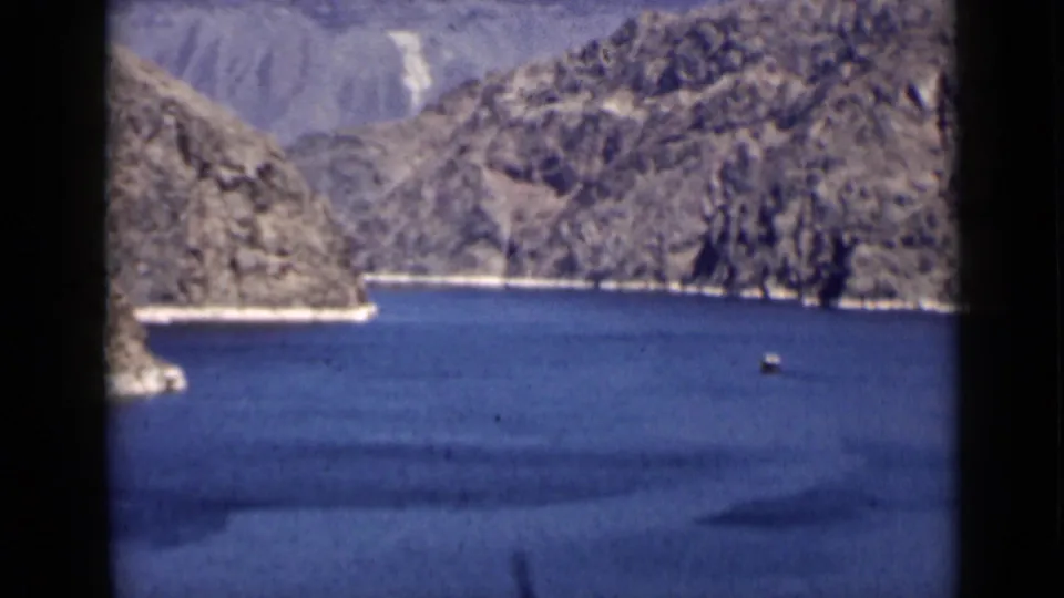 1939 Arizona travel frame showing a blue lake or reservoir between rugged mountains, with a small boat visible on the water.