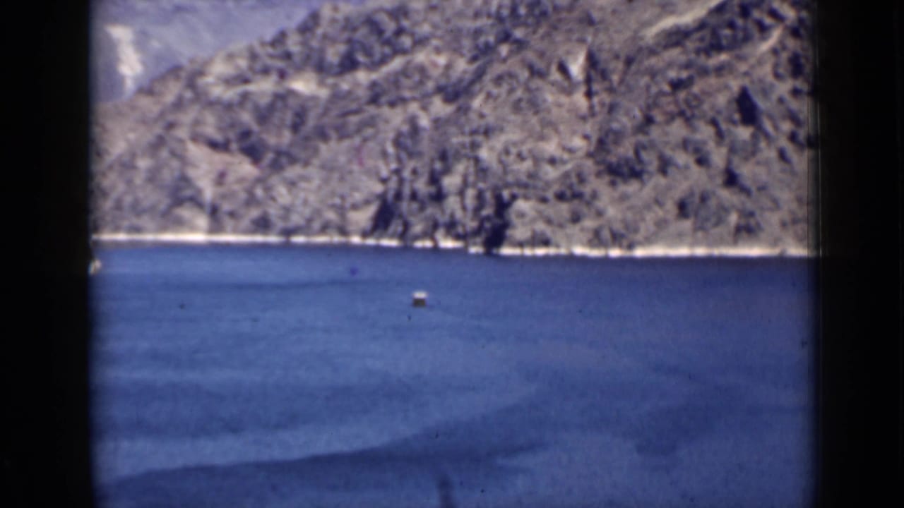 Blue lake water with rugged mountains and a small distant buoy.